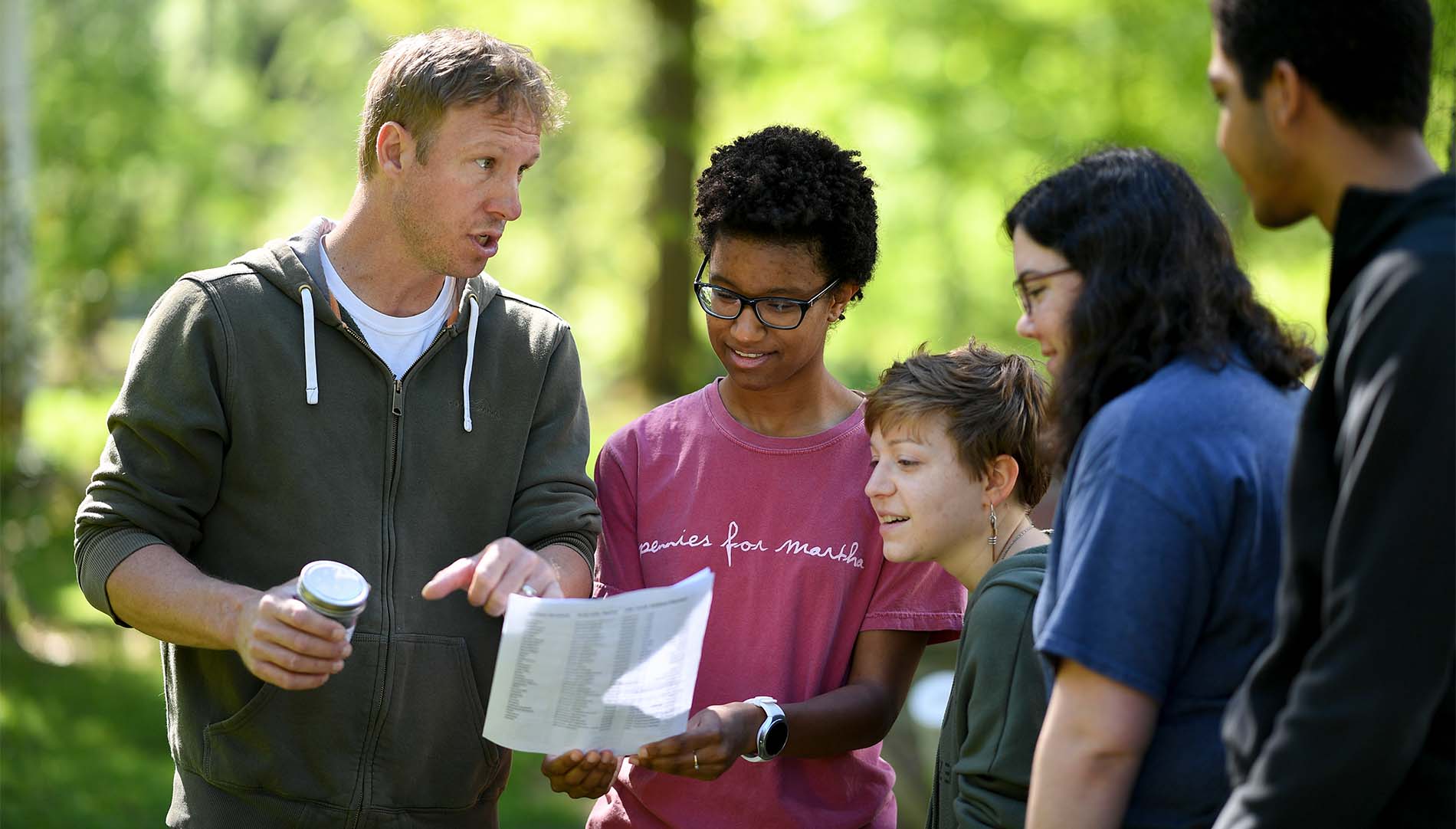 diverse group of students and professor reviewing a document while outdoors